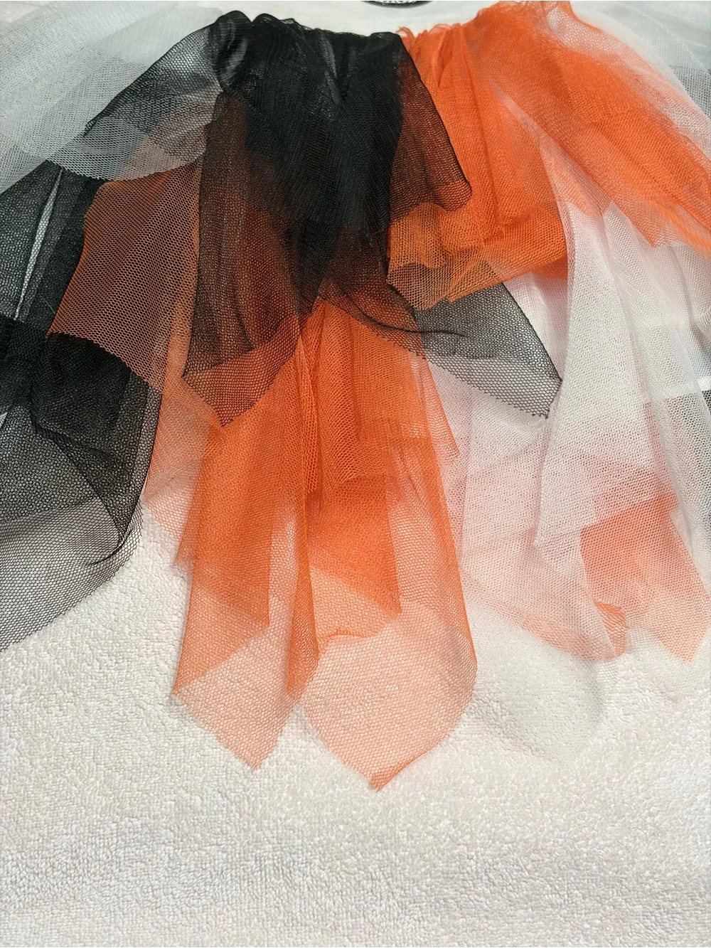 Cutie Halloween costume Has orange, black, and white tulle skirt and wrists.